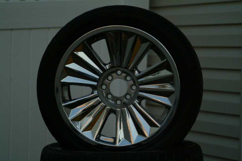 Chrome wheel with many spokes, mounted on a tire. Another tire is visible underneath
