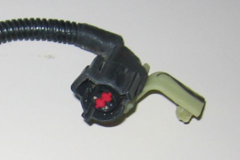 2000 Ford Crown Victoria - Close-up of an electrical connector with visible red inserts and a black ribbed wire loom, likely a vehicle part.