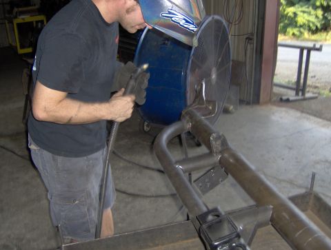1978 Ford Bronco - A person in a welding mask is actively working on a fabricated metal structure, likely a custom part for a vehicle.