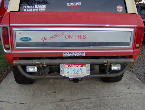 1978 Ford Bronco - The rear of a red Ford Bronco features a custom bumper and several humorous stickers.
