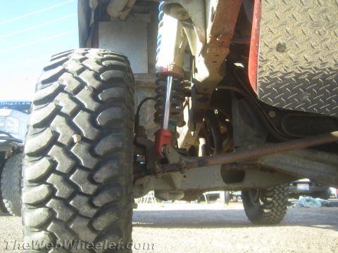 1990 Ford Bronco - low-angle view of a race truck's front suspension showing a chunky off-road tire and a coilover shock.