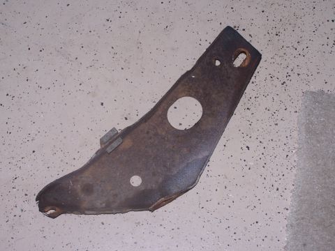 1973 Ford Ranchero - This is a rusted metal bracket, likely a car part, shown on a speckled concrete floor.