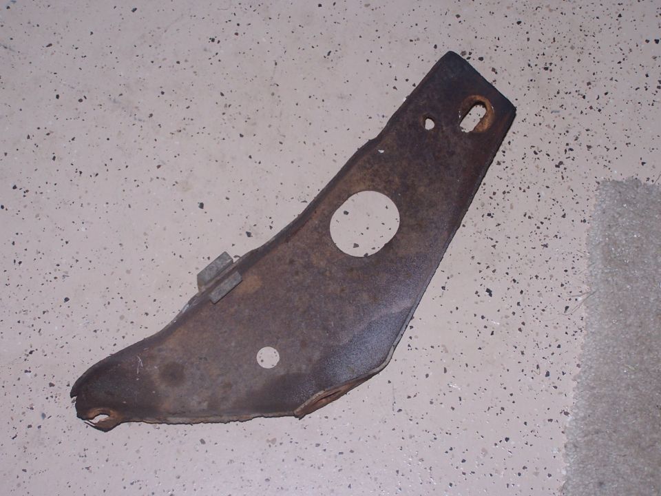 Rusted metal bracket with two circular holes and two rectangular slots