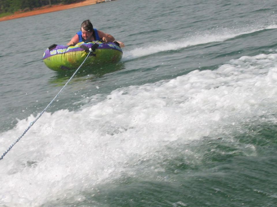 Person riding on a tube being pulled by a boat on a lake