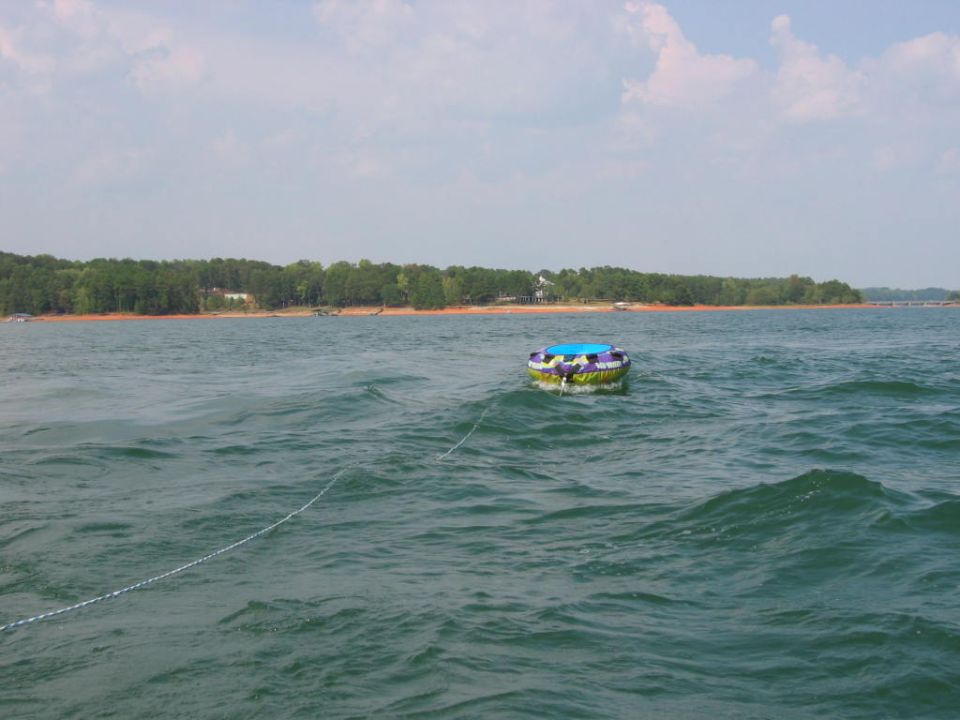 Inflatable towable tube floating on a lake with wooded shoreline behind
