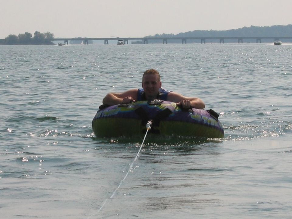 Man in a tube being pulled across a lake, with a bridge in the background