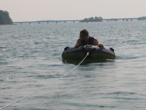 1985 Ford LTD Crown Victoria - A person enjoys a ride on an inflatable tube across Lake Hartwell, SC, with a bridge visible in the distance.