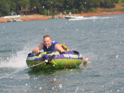 1985 Ford LTD Crown Victoria - A man enjoys tubing on a lake, with another boat in the distance.