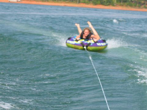 1985 Ford LTD Crown Victoria - A person enjoys tubing on a lake, with the shore visible in the background.