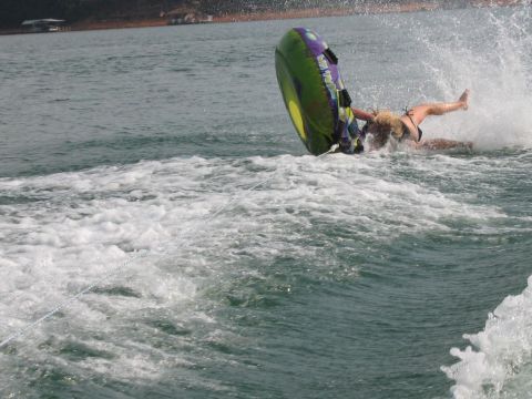 1985 Ford LTD Crown Victoria - A person tumbles off an inflatable tube during a tubing excursion on a lake.