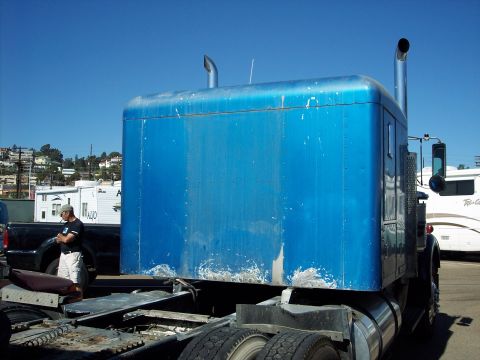 1981 Kenworth W900A - Rear view of a blue semi-truck sleeper cab with visible wear and tear on the lower panels.