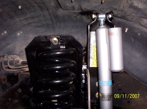 1995 Ford Bronco - Close-up view of suspension components, including a black coil spring and a silver Bilstein shock absorber.