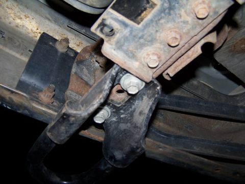 1990 Ford Bronco - Close-up view of a rusty tow hook bracket assembly.