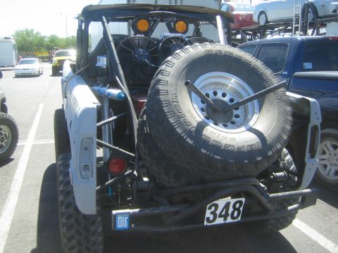 1990 Ford Bronco - Rear view of an open early Ford Bronco race truck numbered 348, showing the mounted spare tire and twin cooling fans.