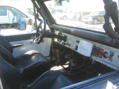 1990 Ford Bronco - Interior of an early Ford Bronco showing the white dashboard, aftermarket switch panel, steering wheel and black bucket seats.