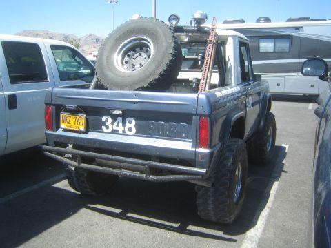 1990 Ford Bronco - Rear quarter view of a dark blue early Ford Bronco numbered 348 with a roof-mounted spare tire and a FORD tailgate badge.