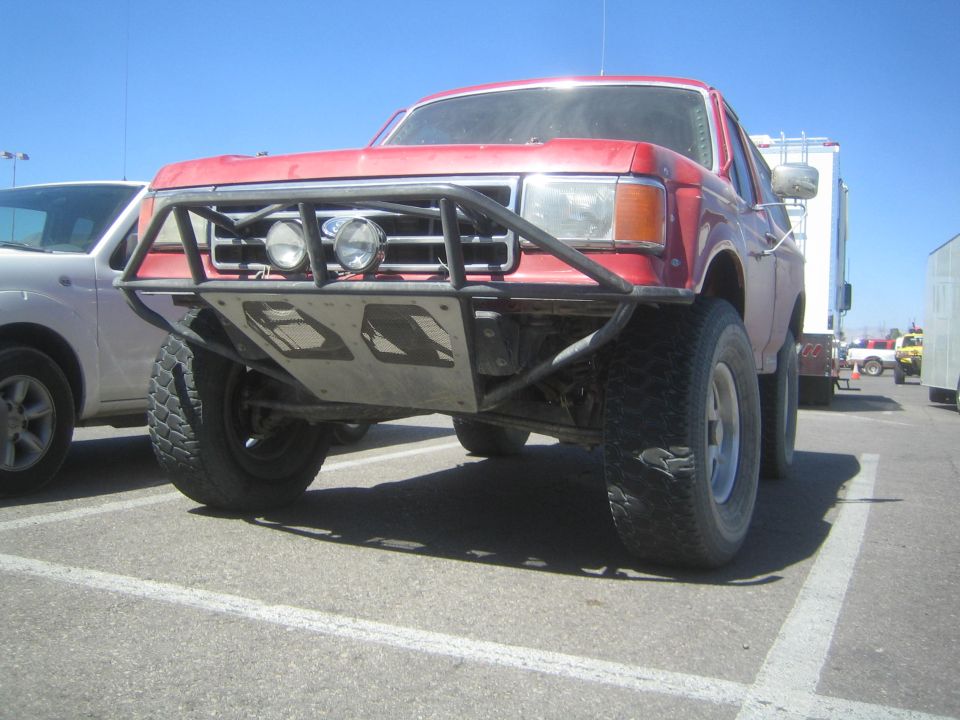 Front quarter of lifted red full-size Ford Bronco with black tube bumper