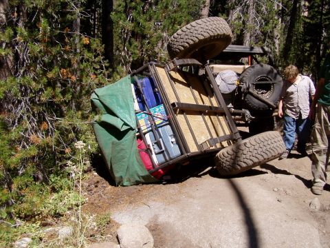 1967 Ford Bronco - An off-road vehicle has overturned on a trail, its trailer also tipped over, with onlookers assessing the situation.