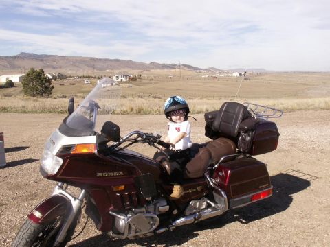 1984 Ford Bronco - A child wearing a helmet sits on a large touring motorcycle with saddlebags and a windshield.