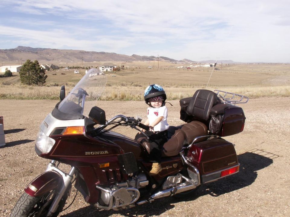 Kid sitting on a big maroon Honda motorcycle in a dry, rural area