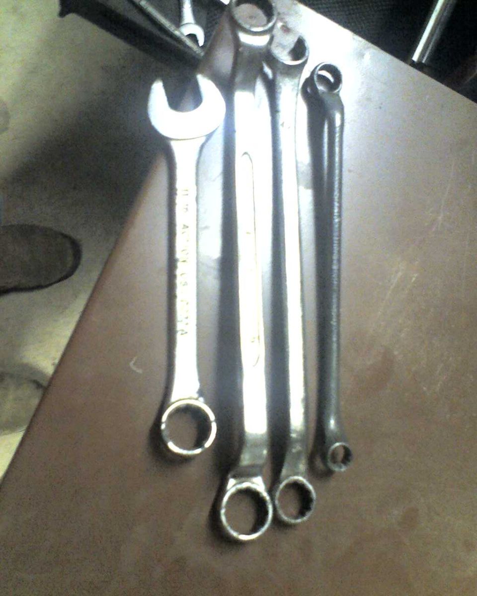 Four metal wrenches on a brown surface, one with visible text