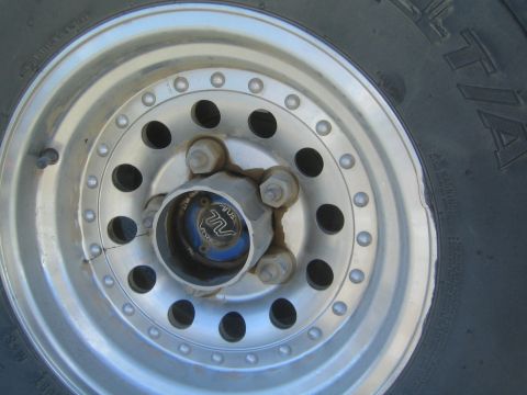1990 Ford Bronco - Close-up of a silver perforated alloy wheel with a locking front hub mounted on a BFGoodrich tire.