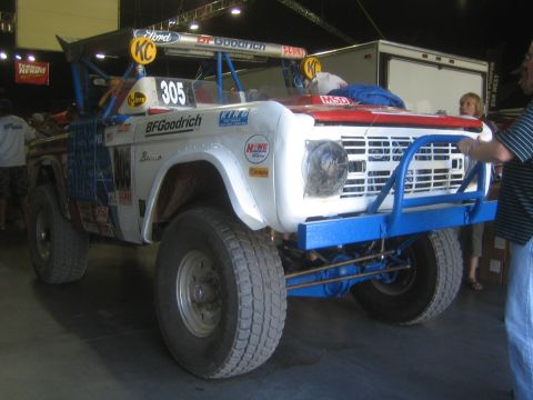 1990 Ford Bronco - Front three-quarter view of a lifted white early Ford Bronco off-road race truck with BFGoodrich and Bronco lettering, number 305.