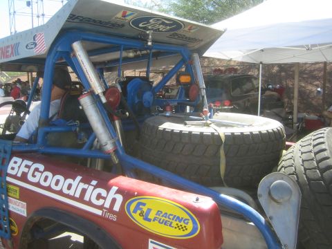 1990 Ford Bronco - Rear detail of an off-road race truck with a blue roll cage, mounted spare tires and BFGoodrich, Ford and F&L Racing Fuel decals.