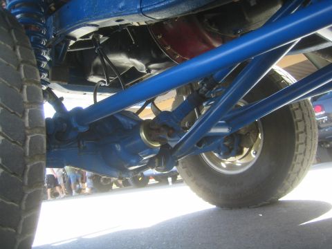 1990 Ford Bronco - Underside view showing the blue painted rear axle, driveshaft and coil-over shocks of an off-road truck.