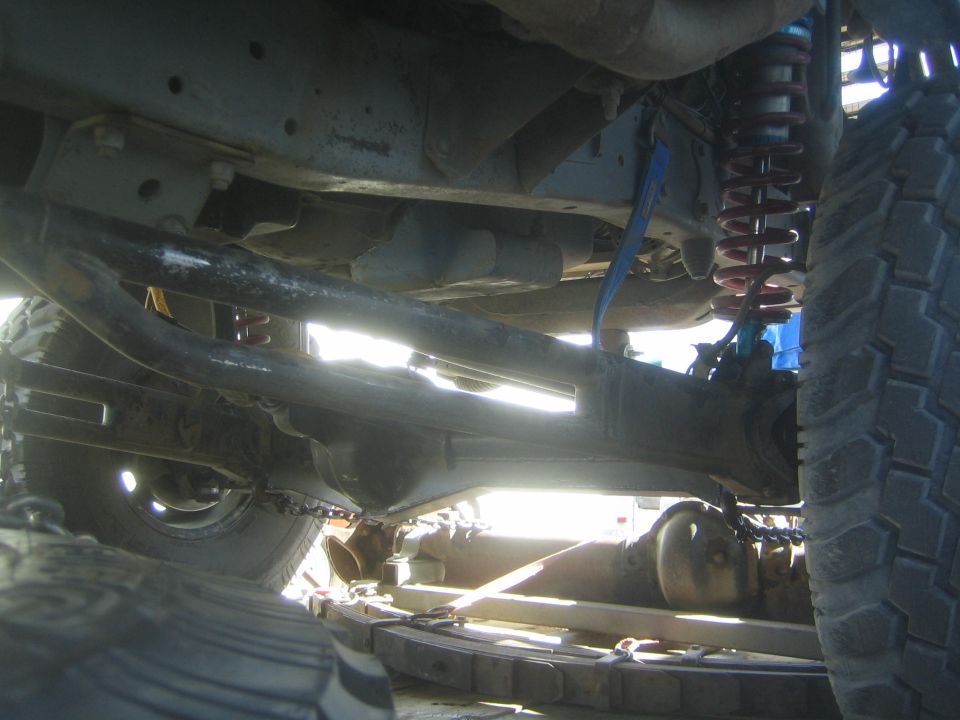 Backlit undercarriage of off-road truck with red shock, axle and chains