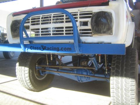 1990 Ford Bronco - Front view of a white early Ford Bronco off-road racer with a blue Class3Racing.com tubular bumper and exposed suspension.
