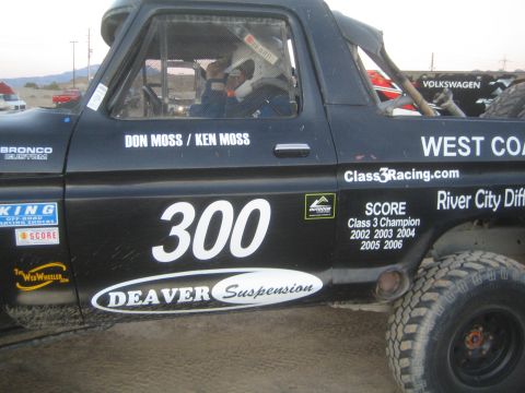 1990 Ford Bronco - Side view of a black race truck numbered 300 lettered Don Moss / Ken Moss with Deaver Suspension and Class 3 Champion decals.