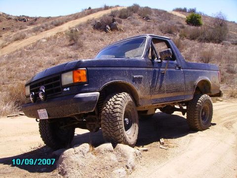 1990 Ford Bronco - 1990 Ford Bronco navigating rough terrain on a sunny day.