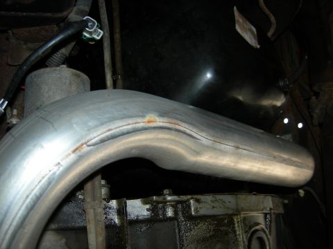 1996 Ford Bronco - Close-up view of an exhaust pipe and transmission components.