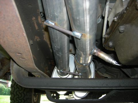 1996 Ford Bronco - Close-up view of a dual exhaust system, including an oxygen sensor and the Supermotors.net logo visible at the bottom right.
