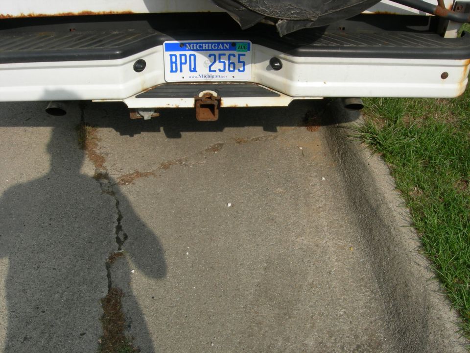 White vehicle rear bumper with a Michigan license plate BPQ 2565 and a trailer hitch