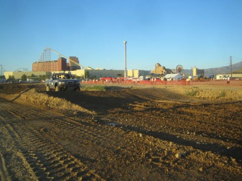 1990 Ford Bronco - off-road truck rolls along a dirt berm course with a casino building, roller coaster and Ferris wheel visible on the horizon.