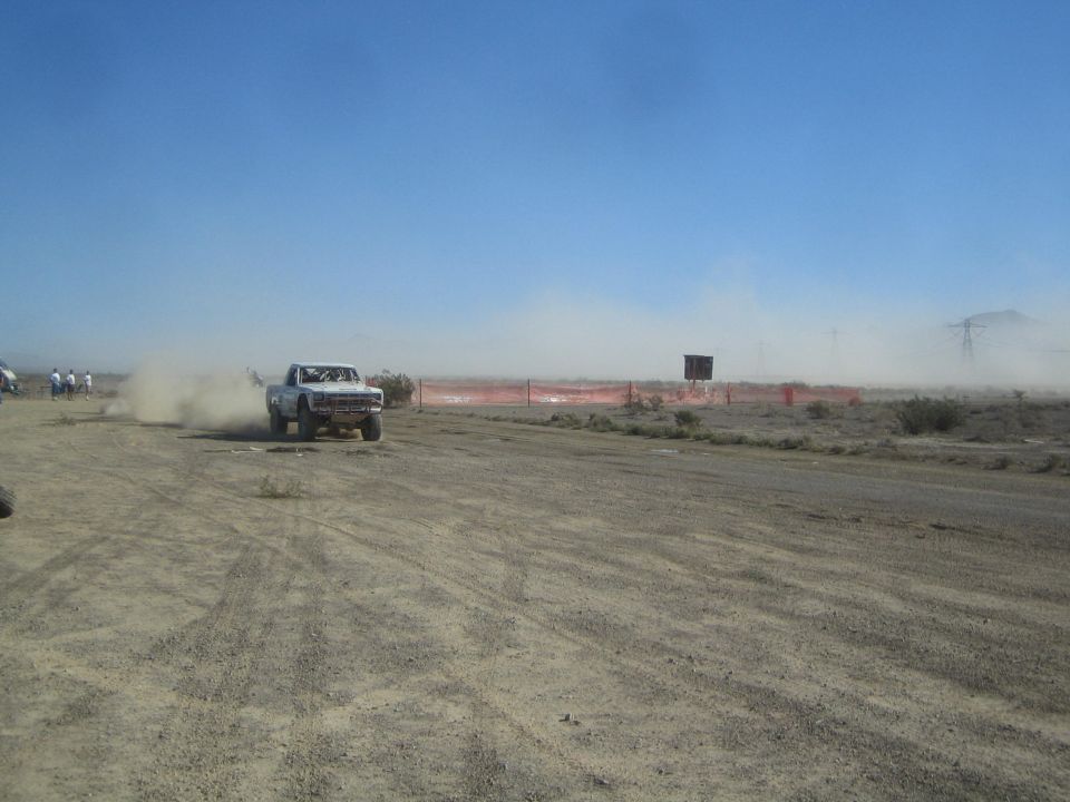 White off-road race truck kicking up dust on a desert dirt course