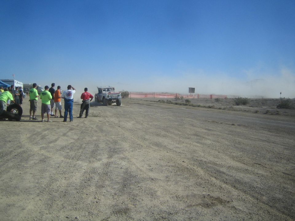 White race truck passing spectators on a desert dirt course