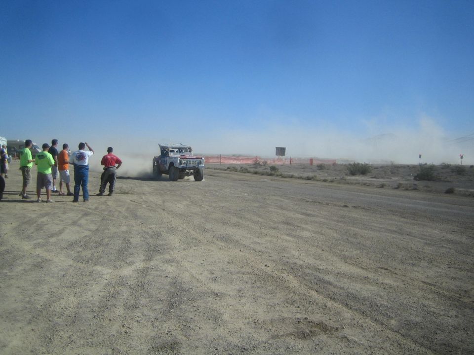 White race truck accelerating past onlookers on a desert track