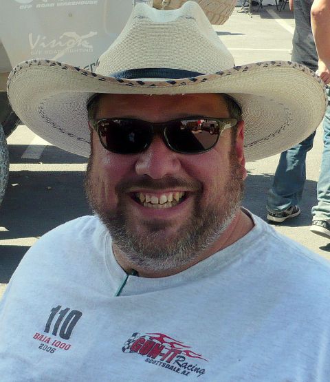 1980 Ford Bronco - Man wearing a cowboy hat and sunglasses smiles, with racing and event logos visible on his shirt.