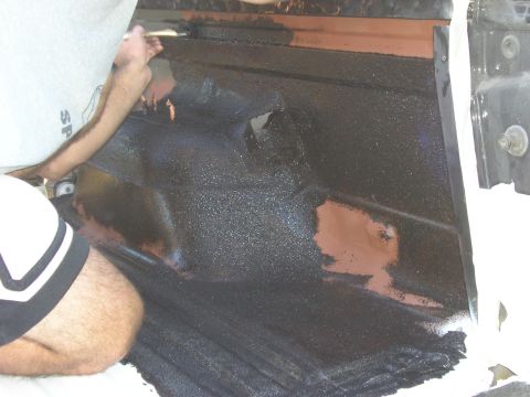 1996 Ford Bronco - A person applies a protective coating to the interior floor of a vehicle.