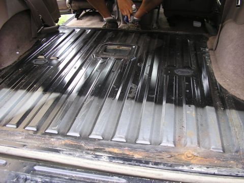 1996 Ford Bronco - Spraying the ribbed interior floor of a vehicle with a protective coating.