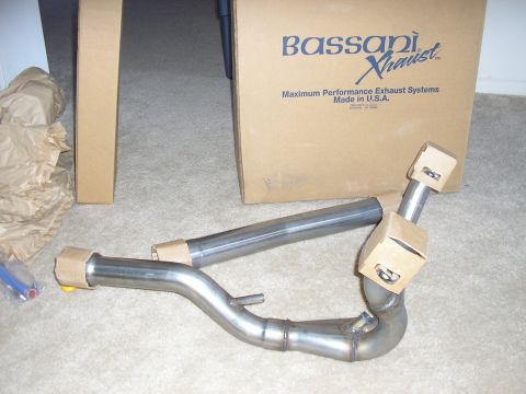 1996 Ford Bronco - A new stainless Bassani Xhaust Y-pipe assembly laid out on carpet with protective caps on the flanged ends and an O2 sensor bung visible on…