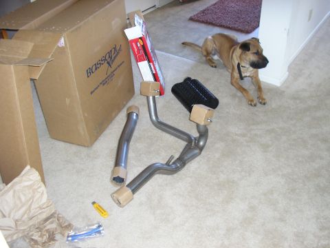 1996 Ford Bronco - A new Bassani Xhaust cat-back exhaust kit unpacked on beige carpet, with the aluminized Y-pipe, tailpipes and a black-cased muffler still w…