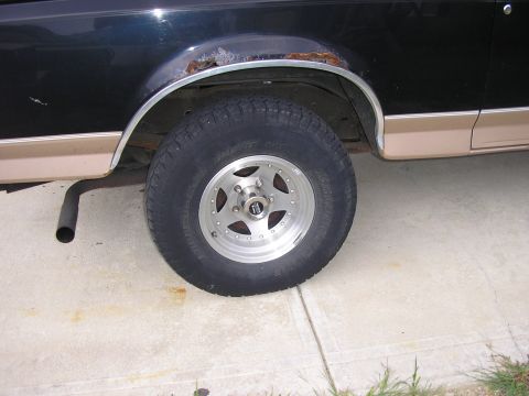 1996 Ford Bronco - Close-up of the rear wheel well on a 1996 Ford Bronco, showing rust on the fender trim.