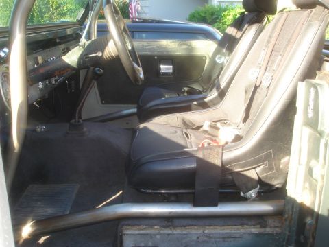 1977 Ford Bronco - The interior of a Ford Bronco features racing seats and a roll cage, with an American flag visible in the background.