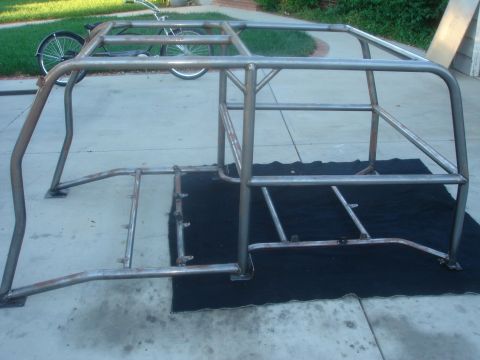 1977 Ford Bronco - A custom roll cage frame is shown on a black tarp, with a bicycle visible in the background.
