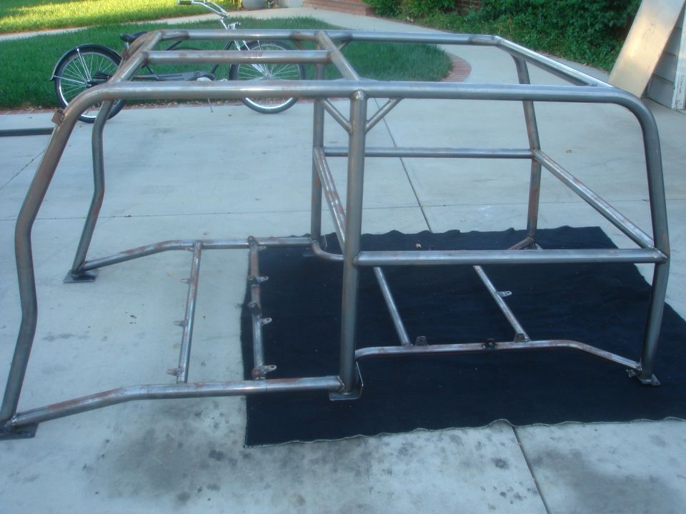 Roll cage frame on black tarp, bicycle in background
