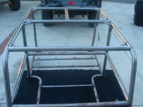 1977 Ford Bronco - Custom roll cage frame being built, with a pickup truck in the background.